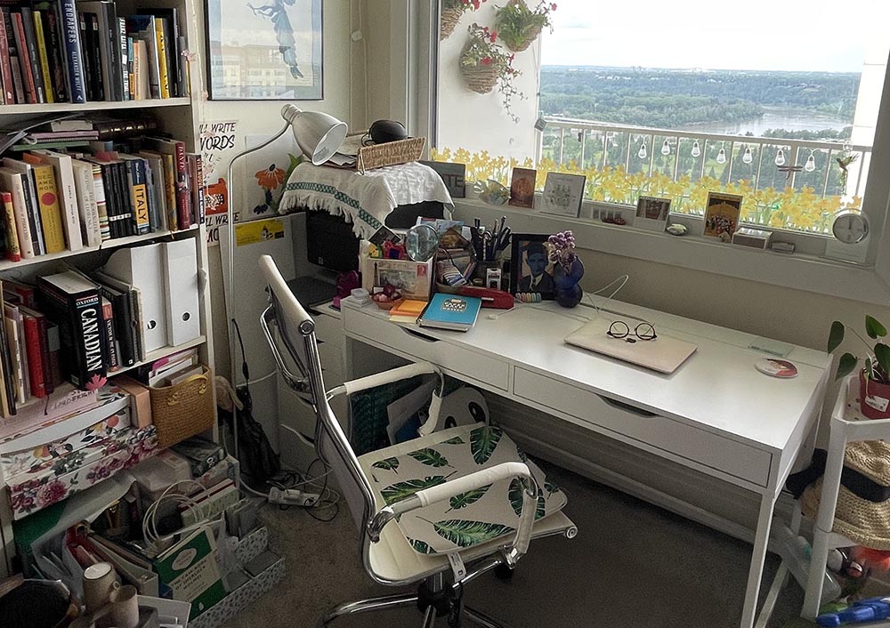 A white desk and chair inside Janice MacDonald's writing studio looking out a beautiful window.